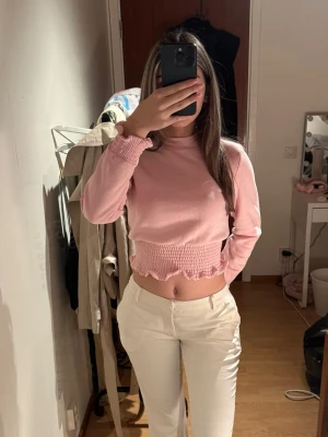 Ljusrosa topp med volang - Supersöt ljusrosa croppad stickad topp med långa ärmar och volangdetaljer i nederkant och vid ärmslut. Har aldrig använt den!💕