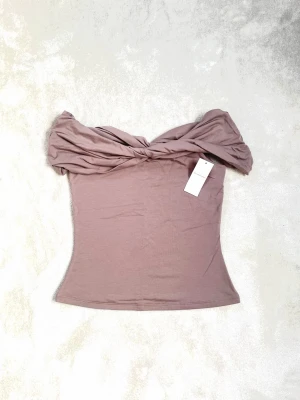 Mocka offshoulder topp Abercrombie - Trendig mocka offshoulder topp från Abercrombie & Fitch, Modal Blend Collection. Toppen har en snygg twistad detalj upptill och är figurnära med axelbandslös design. Perfekt för dig som vill ha en stilren och modern look.