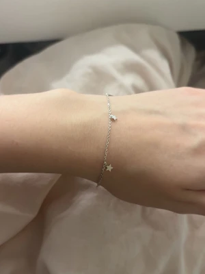 Tunt silverarmband med stjärnor - Säljer ett tunt och stilrent armband i äkta silver (925) med små stjärnformade detaljer längs kedjan. Perfekt för dig som gillar minimalistiska smycken med en söt touch. Lätt att matcha med andra armband eller bära ensamt för en enkel look.