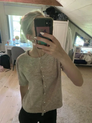 Beige stickad kofta  - Söt beige stickad kofta från Lagrr 157 med korta ärmar och pärlknappar framtill. Koftan har rund halsringning och är gjord i ett mjukt, fluffigt material som känns riktigt mysigt. Säljes då den ej kommer till användning och endast använd fåtal gånger.