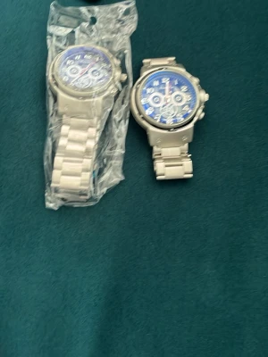 Stilrena silverfärgade armbandsur - Två snygga armbandsur i silverfärg med blå urtavla och metallarmband. Klockorna har flera dekorativa visare och siffror i vitt, vilket ger en modern och sportig look. Perfekta accessoarer för dig som vill ha en cool och tidlös stil.