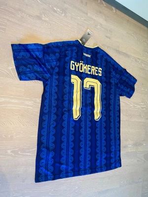 Blå Sverige fotbollströja Gyökeres #17 - Tja! Säljer en helt ny Sveriges VM 2026 Gyökeres #17  T-shirt.                                                                     Den är helt ny , så den har sjuka detaljer! 🤩.                                                                                  Storleken Är Medium, och jag skickar inom 24 Tim💨🤩 hör av dig!
