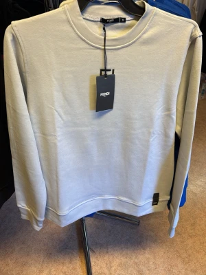 Beige sweatshirt från Fendi - Snygg beige sweatshirt från Fendi med rund halsringning och diskret broderad logga på bröstet. Tillverkad i mjukt material som känns skönt mot huden. Perfekt för dig som gillar stilrena och exklusiva plagg.