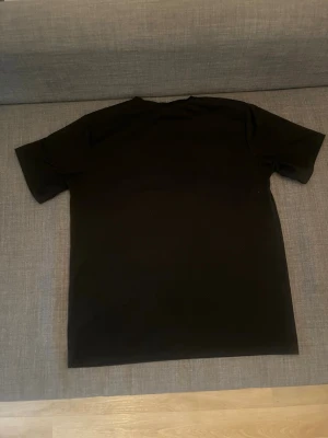 Svart Trapstar t-shirt med tryck - Säljer en svart t-shirt från Trapstar med färgglatt tryck på bröstet där det står 'Trapstar It's a secret' i blått, vitt och rött. Klassisk passform och rund halsringning. Perfekt för dig som gillar streetwear och vill sticka ut.