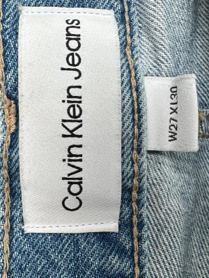 Calvin Klein ljusblå low rise jeans - Snygga ljusblå jeans från Calvin Klein Jeans med low rise och straight fit. Klassisk femficksmodell med silverfärgade knappar och detaljer. Snygg rak modell.