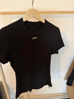Svart Off-White t-shirt - Snygg svart t-shirt från Off-White med diskret 'OFF' broderat framtill vid halsen. Klassisk passform och rund halsringning. Perfekt basplagg för en clean och stilren look OBS. Har klippt nedre delen själv 