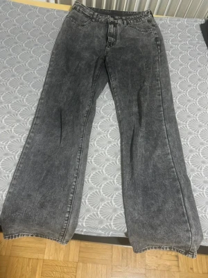 Gråa raka jeans med vintagekänsla - Säljer ett par gråa jeans med rak passform och hög midja. Jeansen har en tvättad vintage-look och klassiska fem fickor. Perfekta för en avslappnad och trendig stil. Materialet är denim i bomull.