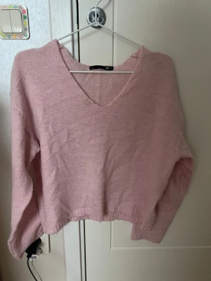 stickad tröja - Mysig ljusrosa stickad tröja från 157 med v-ringning och avslappnad passform. Tröjan har långa ärmar och ribbad nederkant. Perfekt för lager på lager och ger en soft vibe till din outfit. Passar även väldigt bra att bara slänga på sig snabbt men endå har en snygg outfit 