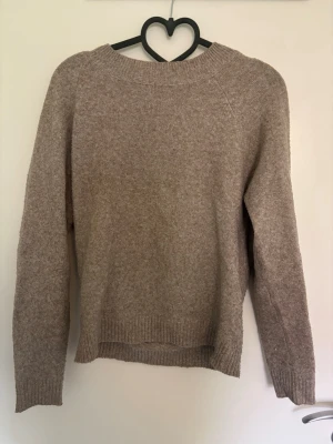 Beige stickad tröja från vero moda - Mysig beige stickad tröja från vero moda med rund halsringning och långa ärmar. Tröjan har en enkel, rak passform och ribbstickade muddar vid ärmslut och nederkant. Perfekt för lager på lager och en avslappnad look.