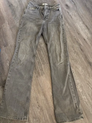 Grå bootcut jeans - Säljer ett par grå jeans med bootcut. Jeansen har klassisk femficksdesign och är tillverkade i denim. Perfekta för en avslappnad och trendig look.