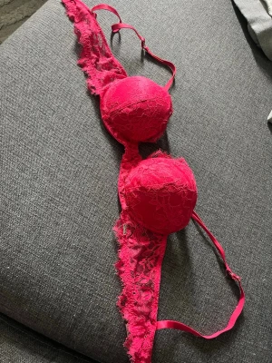Rosa spets-bh med vadderade kupor - Snygg rosa bh med vadderade kupor och spetsdetaljer. Justerbara axelband och tre hakar i ryggen för bästa passform. Spetsen ger en romantisk känsla och bh:n har en feminin design. Perfekt för dig som gillar färg och fina detaljer. Skickas nytvättad! Går att justera axelbandens längd. Är lite push-up inuti.