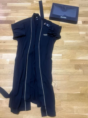  Boss morgonrock, nyskick - Säljer en stilren Boss morgonrock i nyskick, endast använd en gång. Köpt för cirka ett år sedan och har sedan dess legat oanvänd.  Originalförpackning ingår.  En bekväm och exklusiv morgonrock med hög kvalitet perfekt både hemma och efter dusch.  Priset börjar från 700 kr, kan diskuteras vid snabb affär.