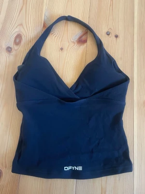DFYNE Origin Halter Top - Säljer denna jättefina halterneck topp från DFYNE med en vacker öppen rygg. Sitter jättefint på kroppen, slutsåld på dera hemsida i varje storlek💓 Loggan på framsidan åkte av k tvätten men det är ingen man tänker på, annars i jättebra skick🖤