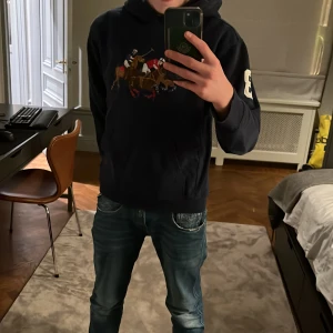 Mörkblå hoodie från Polo Ralph Lauren - Säljer en snygg mörkblå hoodie från Polo Ralph Lauren. Snyggt märke på framsidan och siffran 3 på ärmen. Perfekt för en avslappnad stil. Gjord i mjuk bomull för extra komfort. L i barnstorlekar men passar XS. 