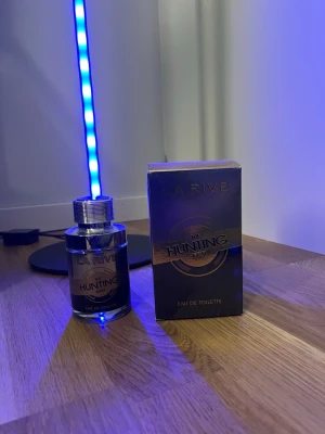 La Rive The Hunting Man EdT - La Rive The Hunting Man Eau de Toilette är en parfym för män med en stilren, rund glasflaska och silverfärgat lock. Förpackningen är mörk med guldiga detaljer och text. Perfekt för dig som gillar maskulina dofter och snygg design.