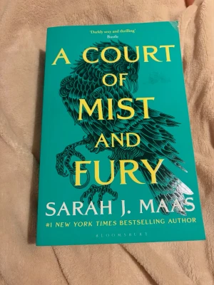 A Court of Mist and Fury & Silver Flames - Två böcker av Sarah J. Maas: 'A Court of Mist and Fury' med turkos omslag och gul text samt 'A Court of Silver Flames' med orange omslag och gul text. Båda har snygga illustrationer på framsidan och är tryckta i mjukpärm från Bloomsbury. Köp en för 120 eller två för 240🤗