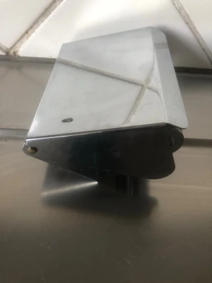 Metallisk väggmonterad hållare - Säljer en väggmonterad hållare i blankt metallmaterial, troligen för papper eller servetter. Den har en stilren, rektangulär form och öppnas med ett handtag på sidan. Passar perfekt i kök eller badrum för enkel åtkomst.