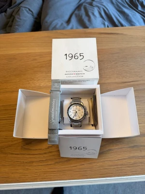 Omega x Swatch Speedmaster klocka - Säljer en stilren Omega x Swatch Speedmaster från Bioceramic MoonSwatch Collection. Urtavlan från en mission to the moon modell har satts in i en stålboett, där det är en stållänk och originalstrapen medgår även i köpet. Klockan har en silverfärgad länk i metall och vit urtavla med svarta detaljer. Kommer i originalbox med extra band. Perfekt för dig som gillar klassiska och ikoniska accessoarer. Visarna har slutat fungera, därav priset. Skickar även med extra länkar. Väldigt bra skick!