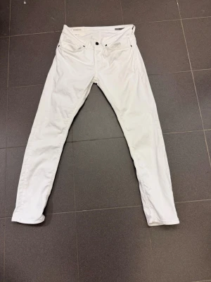 Vita slim fit jeans från Dondup  - Säljer ett par vita slim fit jeans från Dondup. Klassisk femficksmodell med knappgylf och smal passform. Snyggt märke bak i midjan. Perfekta för dig som gillar stilrena och trendiga jeans.