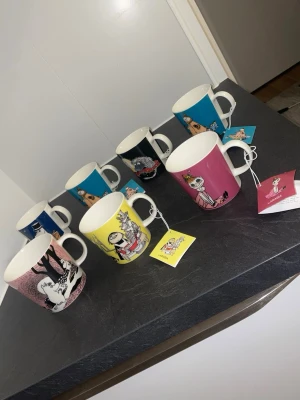 8 stycken Muminmuggar från Arabia - Säljer ett set med åtta färgglada Muminmuggar från Arabia. Muggarna har olika motiv från Muminvärlden och finns i färger som rosa, gul, blå och svart. Perfekta för samlare eller som present! Alla muggar är i porslin och har etiketter kvar. Förutom den mörklblå bak till höger (dock super kvalité)! Den rosa kärleksmuggen är den större varianten. 