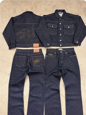 Mörkblå jeans från Stray Rats - Säljer ett par mörkblå jeans från Stray Rats i klassisk rak modell. Jeansen har kontrastsömmar och en broderad logga på bakfickan. Tillverkade i kraftigt denimtyg som ger en schysst streetwear-vibe. Perfekta för dig som gillar stilrena men ändå unika detaljer.