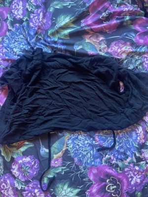 Svart cropped kofta med knytband - Säljer en svart cropped kofta från Gina Tricot med långa ärmar och knytband framtill. Koftan är tunn och har en avslappnad passform, perfekt att slänga över ett linne eller topp. Enkel och stilren design som passar till det mesta.