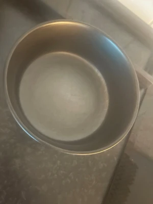 Rund grå kastrull i metall - En enkel rund kastrull i grå metall, perfekt för att koka pasta, ris eller soppa. Kastrullen har släta kanter och saknar synliga handtag eller lock. Passar bra i köket för vardaglig matlagning.