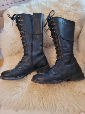 Svarta höga läderstövlar Pandora - Snygga svarta höga stövlar i äkta läder från Pandora For Ever Original. Stövlarna har snörning framtill, dragkedja på sidan och robust sula. Perfekta för en edgy och cool stil.