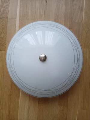 Rund taklampa i frostat glas - Säljer en rund taklampa i frostat vitt glas med tunna, silvriga linjer som dekoration. Lampan har en metallknopp i mitten och plats för tre ljuskällor. Passar perfekt för att ge ett stilrent intryck i rummet.