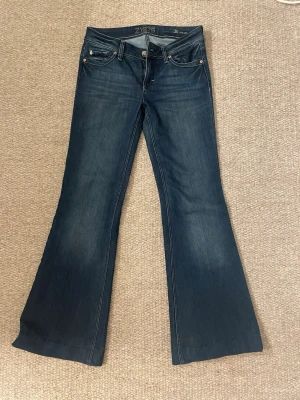 Mörkblå bootcut jeans från  - Snygga mörkblå bootcut jeans från Zips med klassisk femficksdesign och låg midja. Jeansen har utsvängda ben och kontrastsömmar som ger en cool retrovibe. Perfekta för dig som gillar en avslappnad men trendig stil.