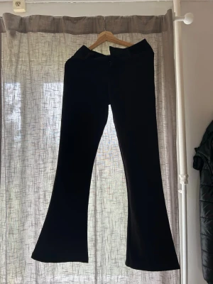 Svarta utsvängda kostymbyxor - Säljer ett par svarta lågmidjade kostymbyxor med utsvängda ben från Gina tricot. Aldrig kommit till användning då dem är lite för korta i benen för min smak, (175 cm). 