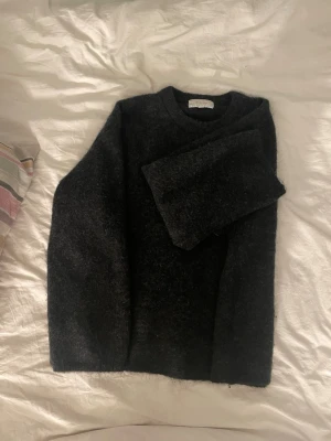Mohair tröja H&M Edition  - Mysig mörkgrå stickad tröja från H&M Edition i storlek XS. Tröjan har en klassisk rak passform med rund halsringning och långa ärmar. Perfekt för lager-på-lager och enkel att matcha med olika outfits.