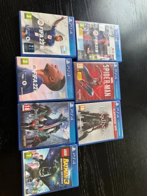 7 PS4 spel:  - Säljer sju PlayStation 4-spel: FIFA 23, FIFA 22, FIFA 21, Spider-Man, Devil May Cry 5, Bloodborne och LEGO Batman 3. Alla spel i blå plastfodral med färgglada omslag. Perfekt för dig som gillar sport, action, äventyr och superhjältar.