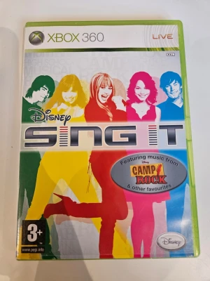 Disney Sing It till Xbox 360 - Disney Sing It är ett musikspel till Xbox 360 där du kan sjunga med till låtar från Camp Rock och andra Disney-favoriter. Omslaget är färgglatt med silhuetter i rött, gult, rosa och blått. Spelet levereras i ett klassiskt grönt Xbox 360-fodral.
