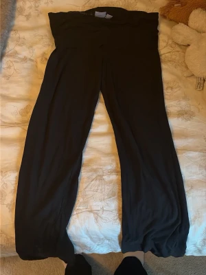 Svarta leggings från Gina Tricot - Säljer ett par svarta leggings från Gina Tricot med hög midja och långa ben. De är tillverkade i ett mjukt och stretchigt material som sitter skönt på kroppen. Perfekta för en avslappnad och trendig look.