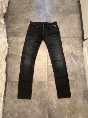 Mörkblå slim fit jeans från G-Star - Snygga mörkblå jeans från G-Star i slim fit-modell. Jeansen har klassisk femficksdesign, låg midja och smala ben. Materialet är denim med lätt tvättad effekt och diskreta detaljer på bakfickorna. Perfekta för en trendig och avslappnad look.