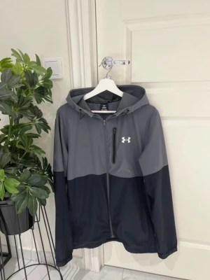 Grå och svart vindjacka Under Armour -  Snygg grå/svart design ✅ Fint skick ✅ Lätt och bekväm passform ✅ Perfekt för träning, fotboll, gym eller vardag ✅ Dragkedjeförsedda fickor 📦 Skickas samma dag eller senast nästa vardag  💰 Pris: 449 kr  Passa på innan den försvinner! Först till kvarn. 🚀  Under Armour, UA, vindjacka, träningsjacka, sportjacka, hoodie, träningskläder, gymkläder, löpning, fotboll, sport, streetwear, herrkläder, unisex, jacka, activewear, workout, fitness, svart jacka, grå jacka, storlek L  #UnderArmour #UA #Vindjac
