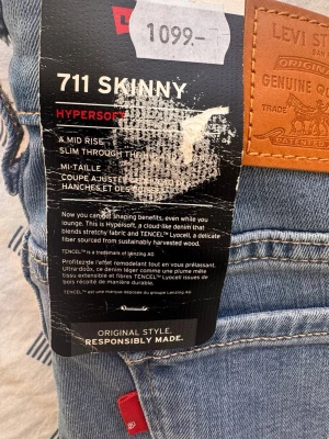 Levi's 711 Skinny ljusblå jeans W24 L30 - Säljer ett par Levi's 711 Skinny jeans i ljusblå tvätt med klassisk läderpatch bak. Modellen har mid rise, smal passform genom benet och är tillverkad i mjukt Hypersoft-denim med TENCEL Lyocell för extra komfort.