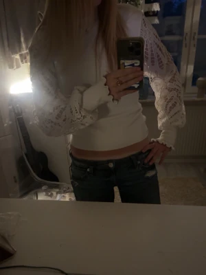 Vit topp med spetsärmar från Moocci - !!PRIS GÅR ATT DISKUTERA!!💗Trendig vit topp från Moocci med croppad passform och långa, transparenta spetsärmar med snyggt hålmönster. Toppen har ribbad struktur i tyget och en enkel, stilren look som passar perfekt till jeans eller kjol. 