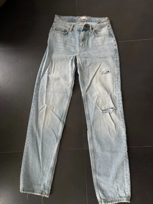 Ljusblå raka jeans med slitningar - Säljer ett par ljusblå jeans med raka ben och snygga slitningar på låren och knäna. De är från Ginatricot i storlek 32. 