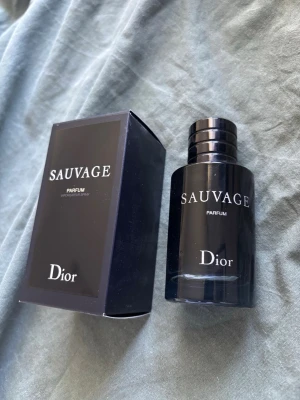 Dior Sauvage Parfum - Dior Sauvage Parfum är en lyxig herrdoft i en elegant mörkblå glasflaska med silverdetaljer. Flaskan har en stilren, rund form och kommer med originalkartong. Doften är intensiv och maskulin, perfekt för dig som vill sticka ut. Ny kostar ungefär 1200kr. Det är lite mer än 40ml ungefär kvar i den.