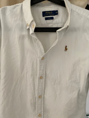 Vit skjorta från Polo Ralph Lauren - Klassisk vit skjorta från Polo Ralph Lauren med button-down krage och broderad logga på bröstet. 