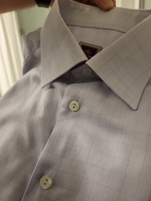Vintage Eton ljuslila grå skjorta L - Klassisk ljusblå skjorta med diskret rutmönster och bröstficka. Skjortan har lång ärm, knappar framtill och en stilren krage. Perfekt för en clean och stilren look. Tillverkad i mjuk bomull för skön känsla hela dagen.