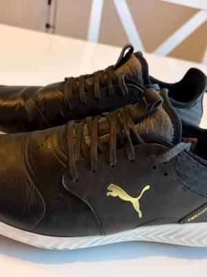 Svarta golfskor från Puma - Snygga svarta golfskor från Puma med guldfärgad logga på sidan. Lite slitage på sulan. 
