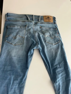 Ljusblå jeans från Replay - Snygga ljusblå jeans från Replay med klassisk femficksdesign och raka ben. Jeansen har tydliga slitningar och kontrastsömmar på bakfickorna. Tillverkade i bomull med en skön passform som sitter bra på benen.