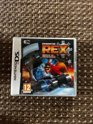 Generator Rex till Nintendo DS - Generator Rex: Agente de Providence till Nintendo DS är ett actionspel baserat på Cartoon Network-serien. Omslaget har en cool tecknad design med Rex i rött och blått, och spelet är på spanska. Perfekt för dig som gillar äventyr och superkrafter!