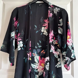 Svart blommig omlott klänning - Svart omlottklänning med blommönster