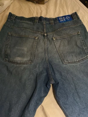 Big Boy blå baggy jeans från Polar - Säljer ett par blå baggy jeans från Polar med Big Boy-patch i blått bak. Jeansen har raka ben två stora bakfickor. Dem är ganska slitna nere vid benen dock. 