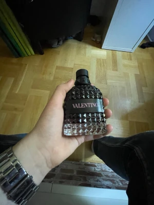 Valentino parfym med nitar (prutbart) - Säljer en snygg parfym från Valentino med en cool flaska i svart och genomskinligt glas, dekorerad med Valentinos kända nitar . Flaskan har en svart etikett med rosa text och ett stilrent lock. Perfekt för dig som gillar exklusiva dofter.