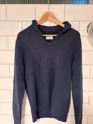Mörkblå stickad tröja med halfzip - Snygg mörkblå stickad tröja från These glory days med halvzip och hög krage. Tröjan har lång ärm och är väldigt skön och mjuk.